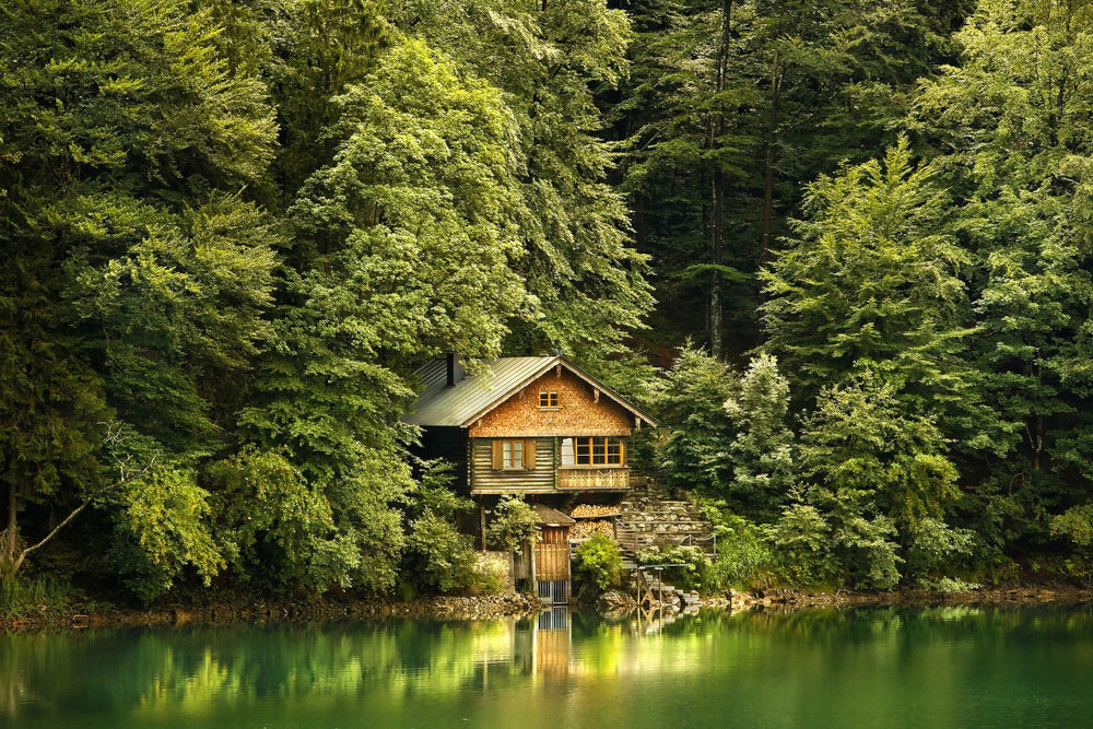 casa em frente a um belo lago, com floresta ao fundo. Foto por Fred Fokkelman